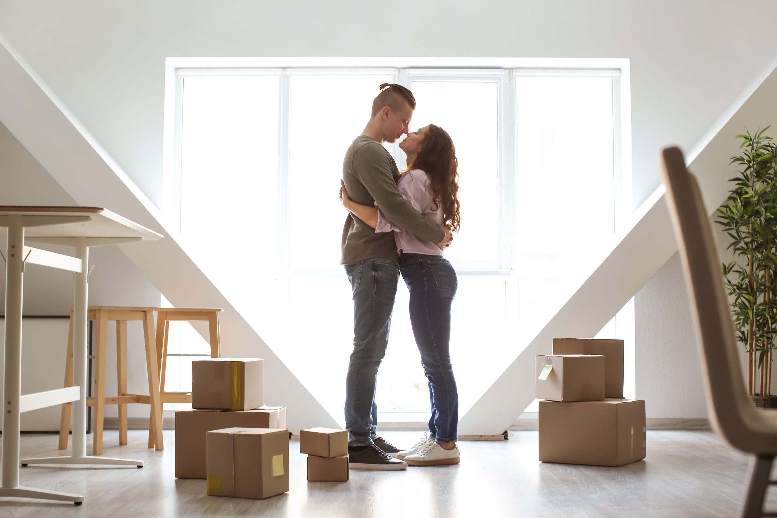 Coppia felice che si abbraccia nella loro nuova casa con scatoloni del trasloco